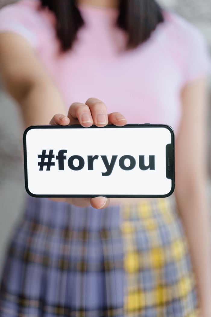 A person holding a smartphone with the hashtag #foryou on the screen, selective focus.
